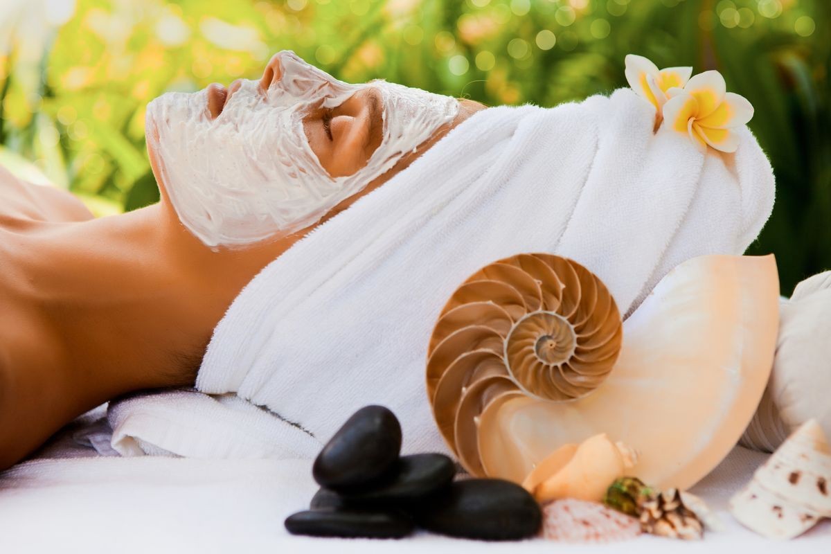 Spa Woman applying Facial clay Mask. Beauty Treatments. Close-up portrait of beautiful girl with a towel on her head applying facial mask