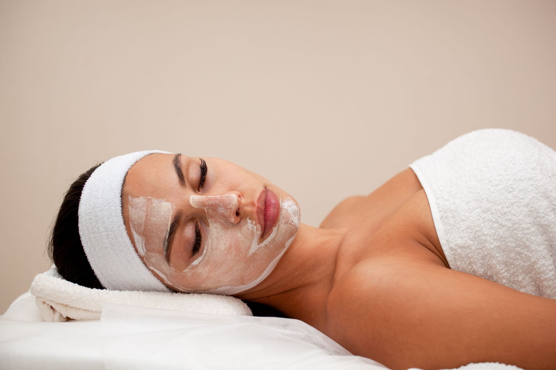 Facemask is a joy. Side view of beautiful young woman in facial mask lying down in spa 
